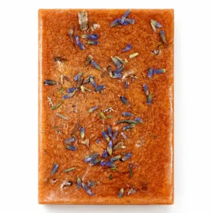 Handmade lavender soap bar with gold mica and dried lavender buds on white background