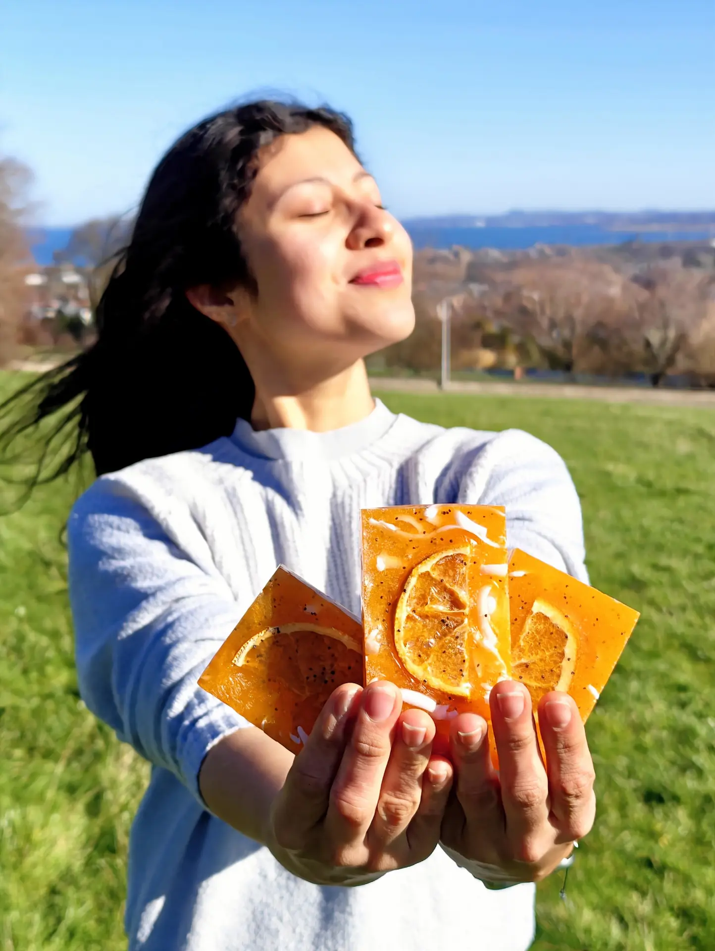 Handmade natural orange soap with dried orange slice held by woman outdoors